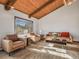 Sun-drenched living room with hardwood floors, wooden beamed ceilings, comfortable seating, and scenic views at 8473 Gray Fox Dr, Evergreen, CO 80439