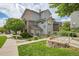 Townhomes with stone facade, light gray siding, lush landscaping, walkway access, and mature trees at 18761 E Water Dr # F, Aurora, CO 80013
