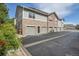Exterior view of townhomes featuring light gray siding and stone accents, plus individual garages at 18761 E Water Dr # F, Aurora, CO 80013