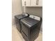 Modern laundry room featuring gray GE washer and dryer with white cabinets above on tile floor at 9843 Rosalee Peak St, Littleton, CO 80125