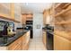 Modern kitchen with granite countertops, light wood cabinets, and black appliances at 1545 Newport St, Denver, CO 80220