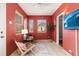 Sunroom features red walls, two armchairs, and plenty of natural light at 1545 Newport St, Denver, CO 80220