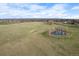 An aerial shot showcasing a large field with a pond and a distant view of a neighborhood at 13804 Quail Ridge Dr, Broomfield, CO 80020