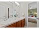 Double vanity bathroom featuring wood cabinets, dual sinks, and bedroom view at 13804 Quail Ridge Dr, Broomfield, CO 80020