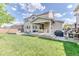 Spacious backyard featuring a lush lawn, covered patio with dining set, and built-in fire pit area at 15389 W 50Th Dr, Golden, CO 80403