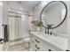 Bright bathroom with a white vanity, black hardware, round mirror, subway tile shower with tub at 15389 W 50Th Dr, Golden, CO 80403