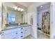 A well-lit bathroom features dual sinks, ample counter space, decorative mirrors, and a shower-tub combo at 15389 W 50Th Dr, Golden, CO 80403