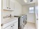 The well-lit laundry room features a sink, white cabinets, and a modern washer and dryer set at 15389 W 50Th Dr, Golden, CO 80403