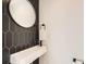 Modern powder room featuring a black accent wall, a unique sink and an oval mirror at 1660 Utica St, Denver, CO 80204
