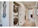 Hallway laundry closet with stacked washer and dryer, and open door revealing neutral-toned carpet, leading to a bathroom at 6570 Parterre N Pkwy # 2, Thornton, CO 80602