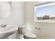 Bathroom with toilet, sleek pedestal sink, a large window, and a neutral color palette at 27460 E Cedar Pl, Aurora, CO 80018