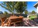 Outdoor dining area in backyard with wood table, bench seating, and mature trees at 5419 Uinta St, Denver, CO 80238