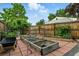 Fenced-in backyard with raised garden beds, brick patio, and mature trees at 6205 Pierce St, Arvada, CO 80003