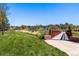 Picturesque park with lush green grass, mature trees, and a charming bridge on a clear day at 6205 Pierce St, Arvada, CO 80003