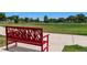 Red metal park bench overlooking the green space at Ralston Central Park at 6205 Pierce St, Arvada, CO 80003