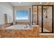 Luxurious bathroom with jetted tub, a tiled shower with glass door, and a large window with blinds at 23593 E Eads Dr, Aurora, CO 80016
