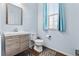 Stylish powder room with a modern vanity, a mirror, and a toilet, illuminated by natural light from the window at 19120 E Pacific Pl, Aurora, CO 80013