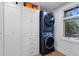 Practical laundry room with stacked washer and dryer units, built-in storage, and natural light at 4121 S Cherry St, Cherry Hills Village, CO 80113