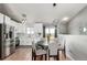 Bright dining area featuring a round table, stylish chairs, and modern lighting fixture, next to kitchen with stainless appliances at 3296 S Bryant St, Englewood, CO 80110