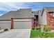 View of the home's exterior highlighting the two car garage, front lawn and partial brick facade at 9403 Southern Hills Cir, Lone Tree, CO 80124