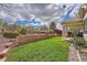 Spacious backyard featuring a manicured lawn, tiered landscaping, and a sturdy black metal fence at 23808 E Bellewood Dr, Aurora, CO 80016