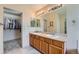 Well-lit bathroom with double sinks, a large mirror, and a walk-in closet for ample storage at 23808 E Bellewood Dr, Aurora, CO 80016