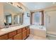 Bright bathroom featuring double sinks, a separate tub, and a glass-enclosed shower with natural light at 23808 E Bellewood Dr, Aurora, CO 80016