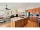 Well-lit kitchen with light wood cabinets, a spacious center island, stainless steel appliances, and hardwood flooring at 23808 E Bellewood Dr, Aurora, CO 80016