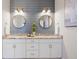 Beautiful bathroom featuring a double vanity with granite countertop, stylish mirrors, and modern lighting at 8505 S Tibet Ct, Aurora, CO 80016