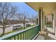 Scenic porch view with green railing overlooking a quiet street with mature trees and parked cars at 375 Longspur Dr, Brighton, CO 80601