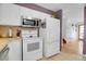 A kitchen featuring white appliances and cabinets, with easy access to a hallway at 960 S Arbutus St, Lakewood, CO 80228