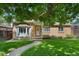 Charming brick home with bay window, lush lawn, and mature tree providing shade at 1080 S Garfield St, Denver, CO 80209