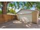 Rear view of a one car detached garage and parking pad with mature landscaping at 1080 S Garfield St, Denver, CO 80209