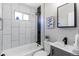 Contemporary bathroom features a shower-tub, modern fixtures, and white tiling throughout at 7856 Ladore St, Commerce City, CO 80022