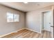 Bright bedroom featuring wood floors, neutral walls, and a door leading to the hallway at 7856 Ladore St, Commerce City, CO 80022