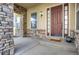 Inviting front porch featuring a stone support column and trim and a paneled front door with sidelights at 5480 Craftsman Dr, Parker, CO 80134