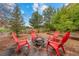 Inviting backyard with a stone fire pit and bright red Adirondack chairs, creating a perfect outdoor gathering spot at 5791 Chisholm Pl, Parker, CO 80134
