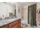 Bathroom featuring granite countertop, wood cabinets, toilet, and shower with decorative shower curtain at 5791 Chisholm Pl, Parker, CO 80134