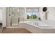 Bright bathroom features a soaking tub, glass enclosed shower, window, and tile flooring at 5791 Chisholm Pl, Parker, CO 80134