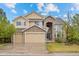 Inviting two-story home featuring a stone archway, three-car garage, and mature landscaping at 5791 Chisholm Pl, Parker, CO 80134