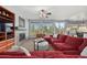 Cozy living room with a fireplace, plush red sectional, and large windows at 5791 Chisholm Pl, Parker, CO 80134