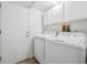 Well-lit laundry room features overhead cabinets and modern washer and dryer at 15942 E Rice Pl # B, Aurora, CO 80015