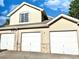 Three car garages with neutral paint, stone accents, and white doors at 2247 Coronado Pkwy N #D, Denver, CO 80229