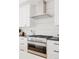 Close up of a modern gas range with stainless steel hood and white subway tile backsplash at 4139 Benton Street, Denver, CO 80212