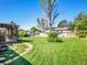 Large backyard with a lush green lawn, mature trees, a patio area, and a charming pergola at 13133 Regulus Dr, Lone Tree, CO 80124