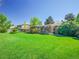 Beautiful backyard with a well-maintained lawn, mature trees, and a cozy covered patio area at 13133 Regulus Dr, Lone Tree, CO 80124