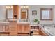 Spacious bathroom with wooden double vanity, bathtub, and open shelf storage at 6839 Estes Dr, Arvada, CO 80004