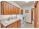 Well-organized laundry room with wood cabinets, a utility sink, and modern front-loading washer and dryer at 6839 Estes Dr, Arvada, CO 80004
