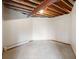 Unfinished basement space with concrete floor, white walls, and exposed ceiling beams at 1961 S Xenia Ct, Denver, CO 80231