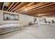 Large basement featuring exposed wood ceiling beams, cement floors, and multiple windows at 1961 S Xenia Ct, Denver, CO 80231
